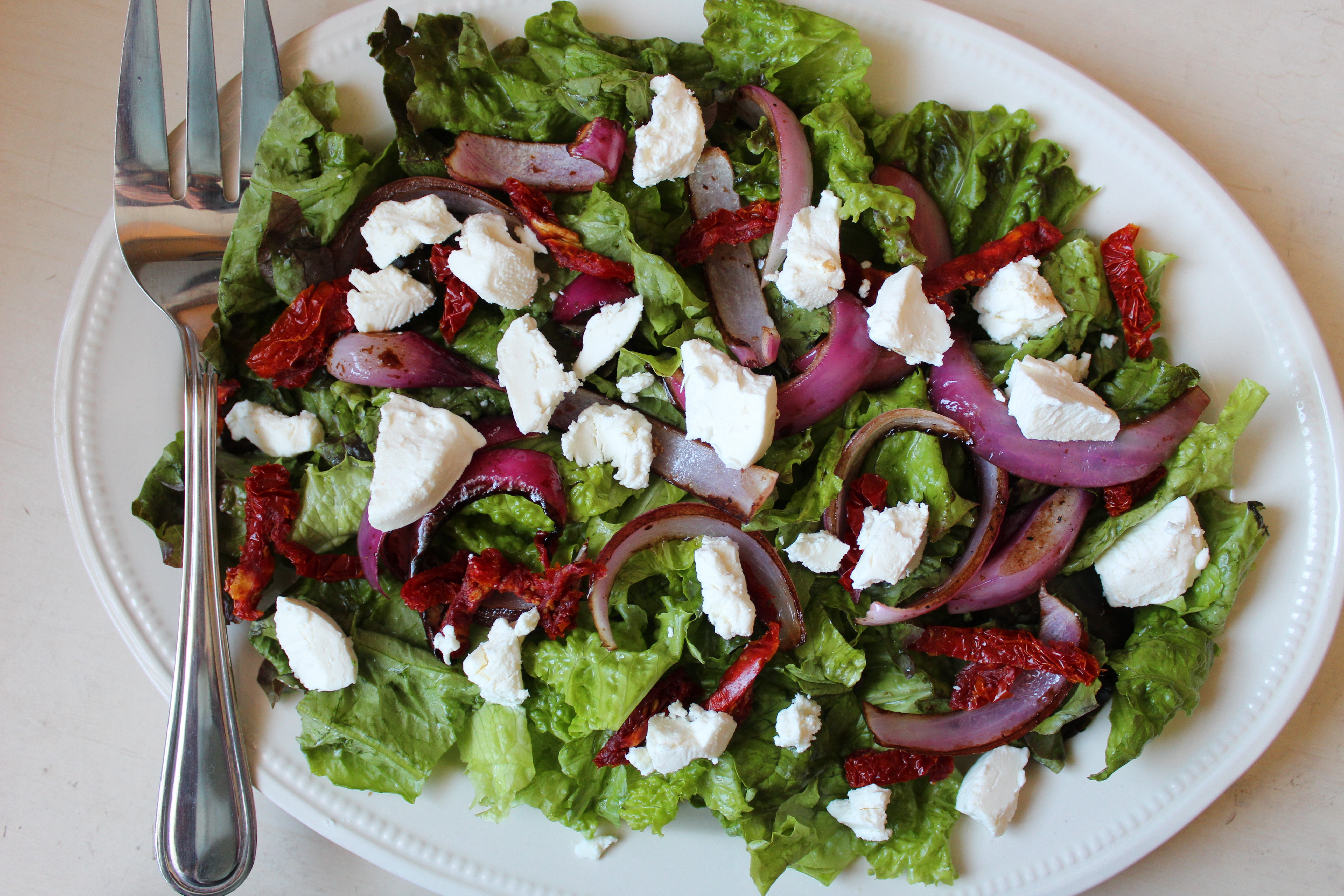 Full of flavorful ingredients like goat cheese, sun dried tomatoes, and roasted onions, then dressed with a balsamic vinaigrette, this salad comes together quickly and simply. Serve it as an appetizer or an easy lunch!