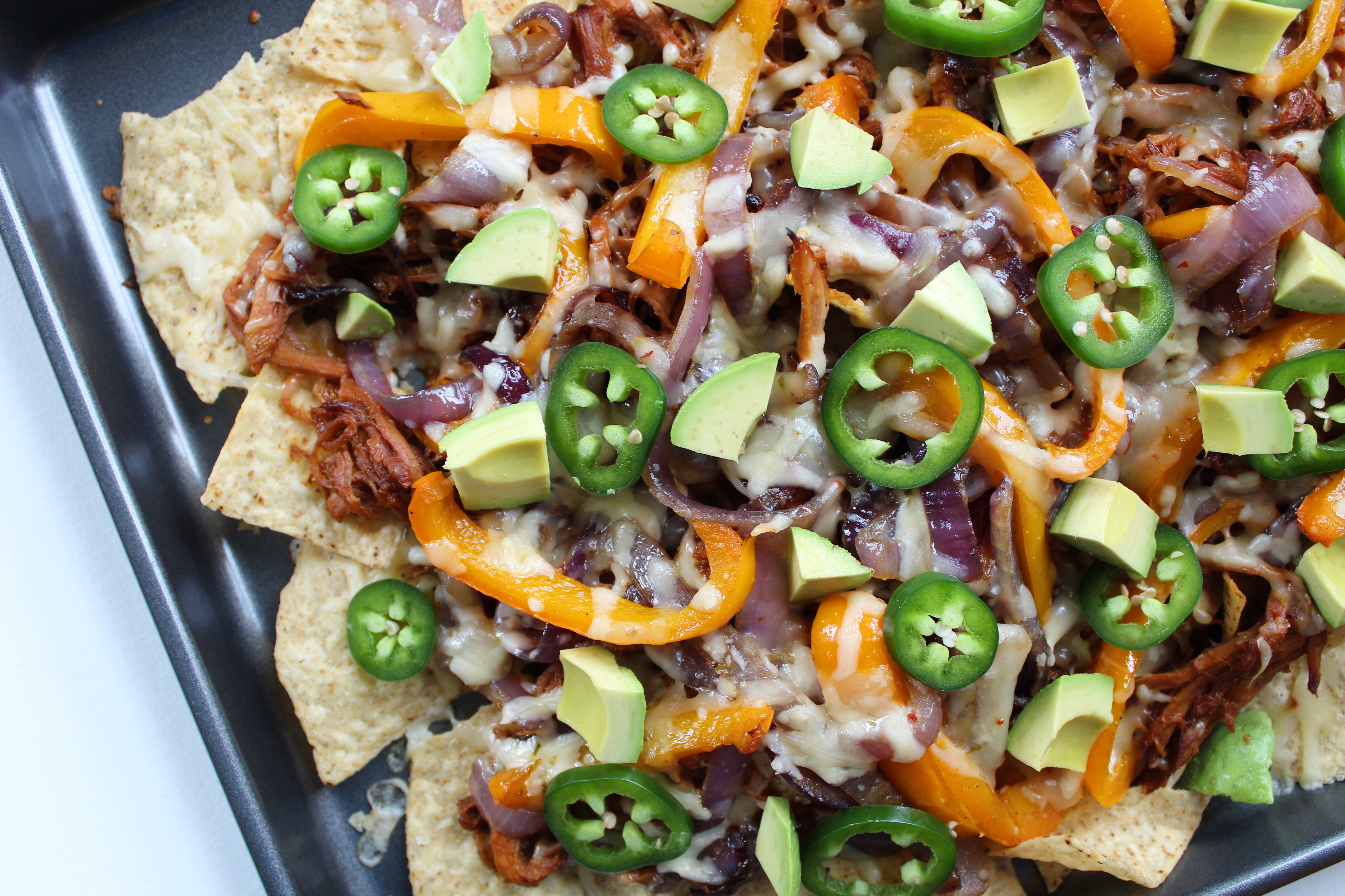 These nachos are topped with BBQ pork, fajita-style peppers and onions, and more fun toppings, and they'll make great party food!